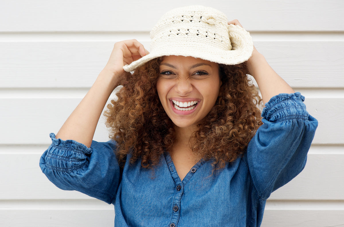 Black woman looking at her natural hair in a mirror while detangling it
