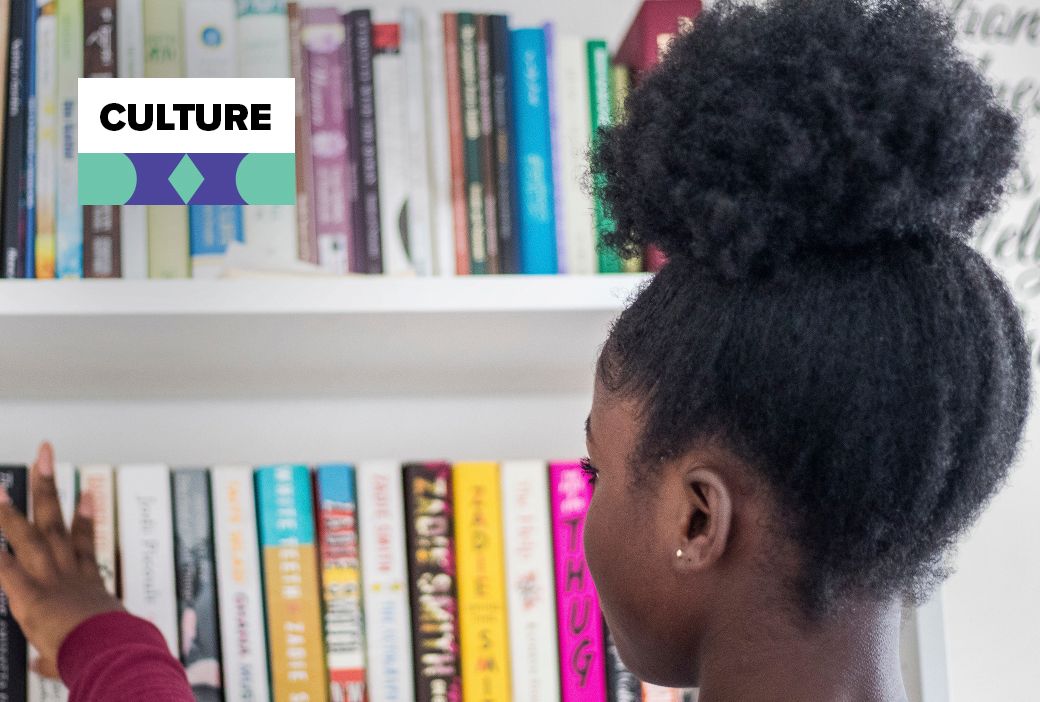 Children books about natural hair stacked beside a doll with curls