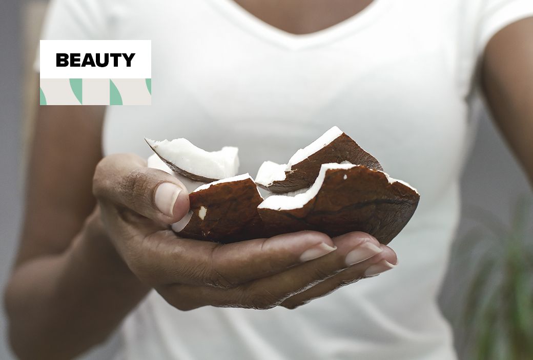 Jar of coconut oil open beside hair and skincare tools