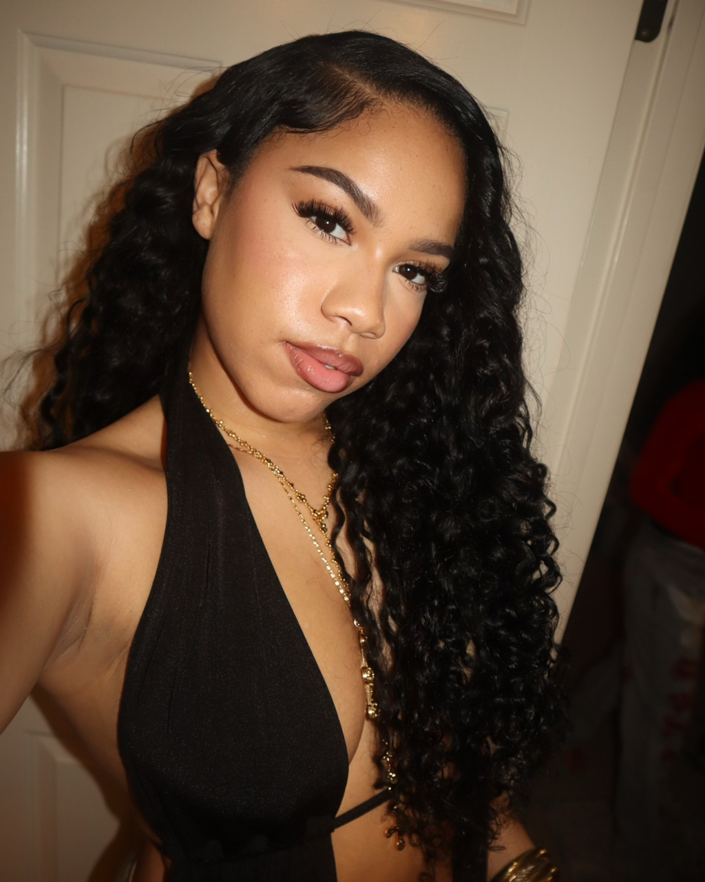 Natural black Brazilian deep wave bundle coiled on a plain background