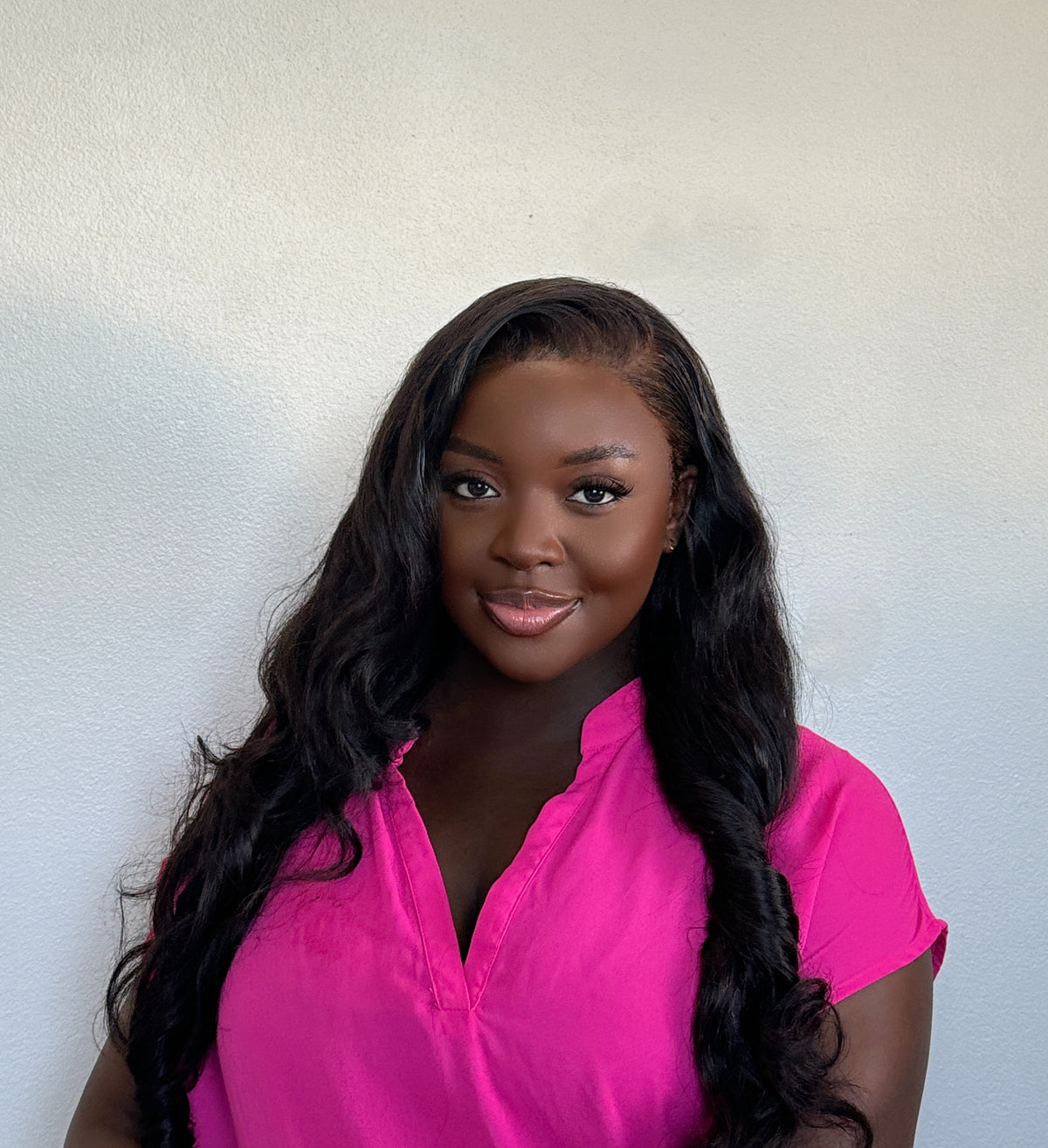 Smiling woman in a pink shirt wearing long, black bouncy curls