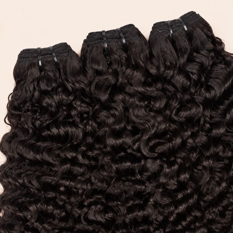 Three Burmese curly bundles angled to show the machine-sewn wefts
