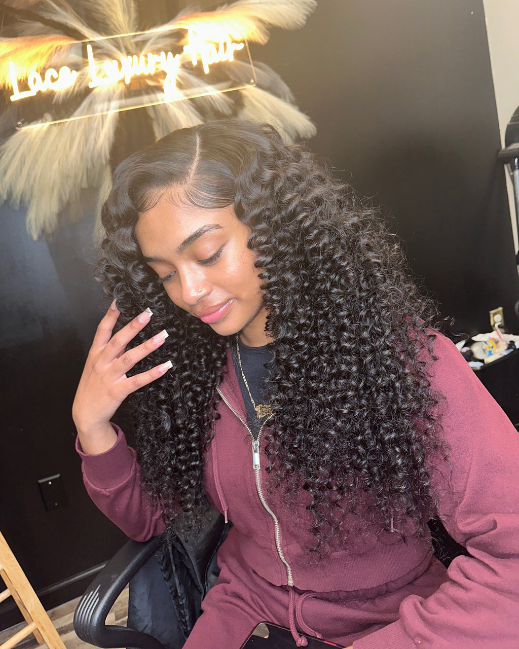 Model smiling in a natural black Brazilian deep wave sew-in, three quarter view