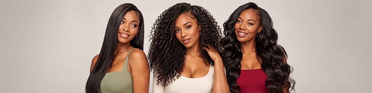 Three women modeling long, wavy black hair extensions or hairpieces against a plain light gray studio background.