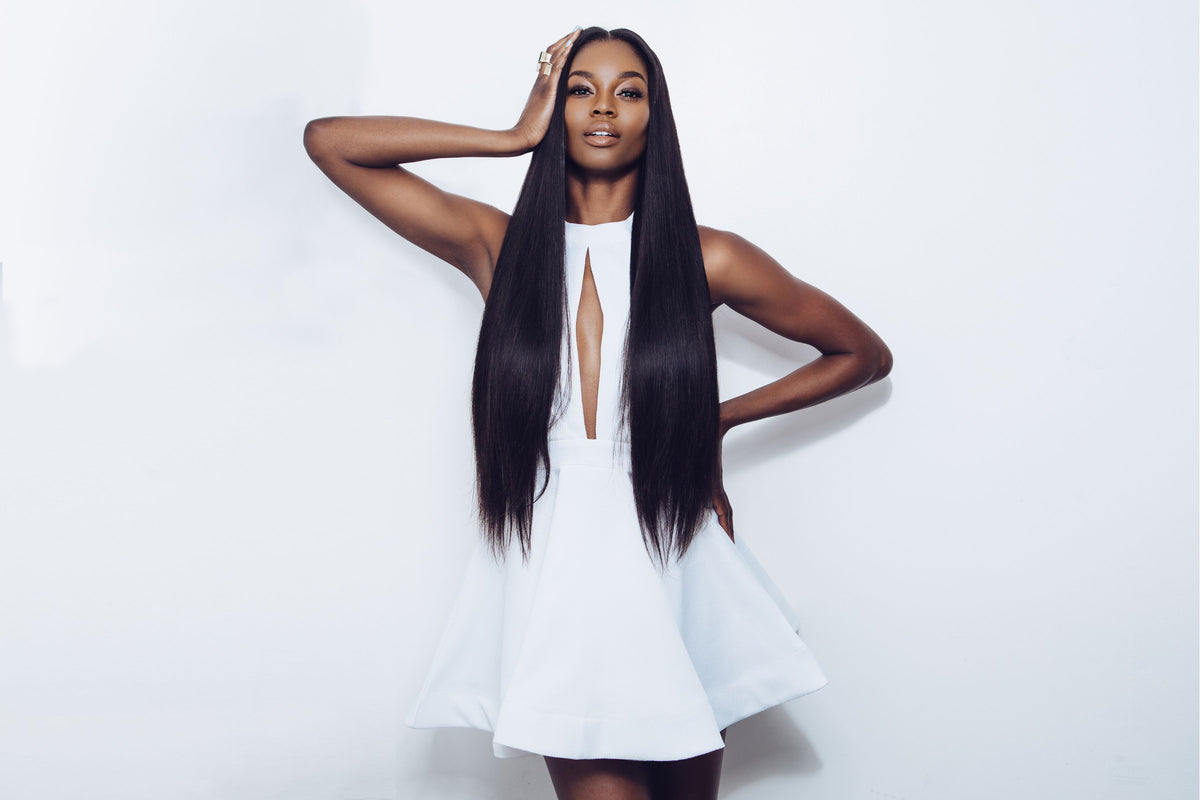 A woman with extremely long, straight, black human hair bundles from Mayvenn wearing a white sleeveless dress, posing against a clean white studio background.