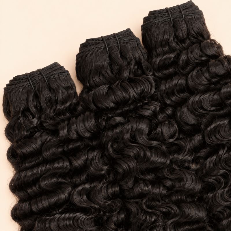 Three raw Burmese curly bundles angled to show the machine-sewn wefts