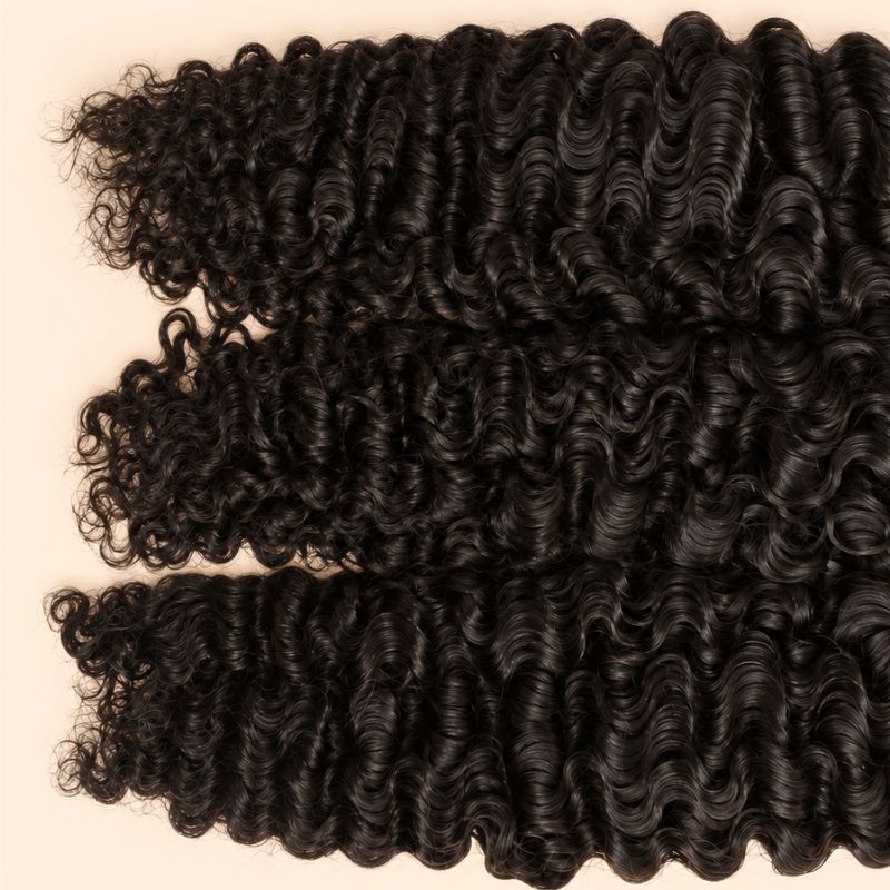 Three raw Burmese curly wefts laid flat, showing the staggered lengths