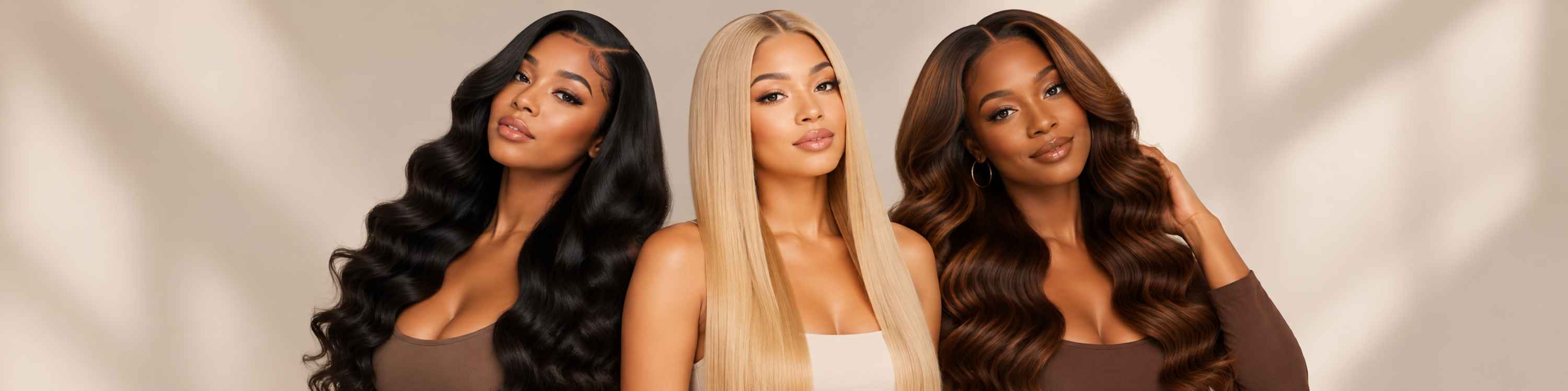 Three women modeling long, wavy synthetic or human hair extensions in different colors: black, blonde, and brown. They are standing against a warm beige background with soft leaf shadows.