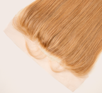 Close-up of transparent lace along a honey blonde straight frontal hairline