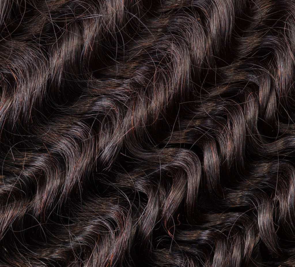 Hand holding a natural black Brazilian deep wave bundle to show weft quality