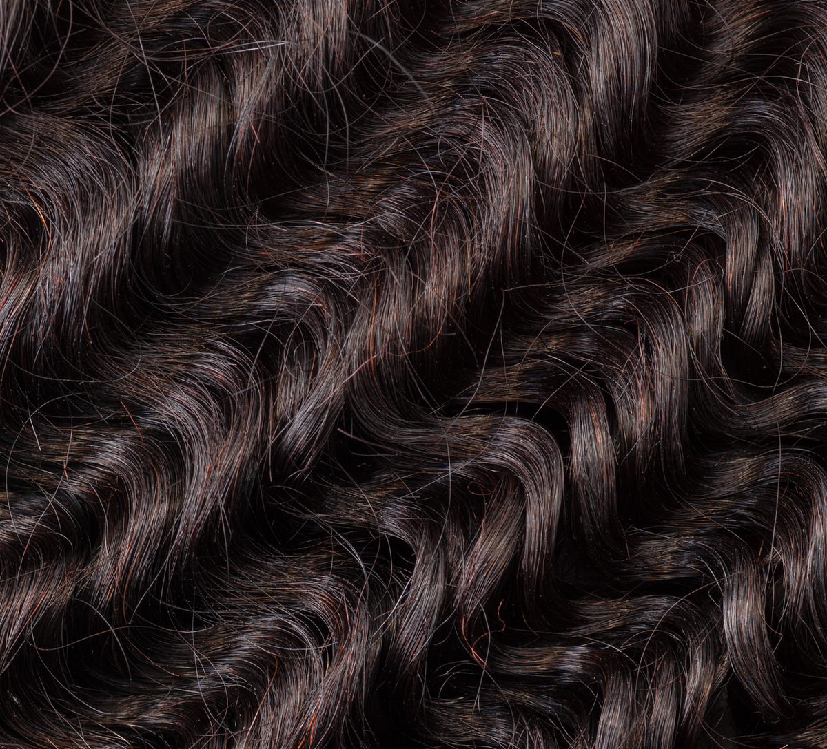 Hand holding a natural black Brazilian deep wave bundle to show weft quality