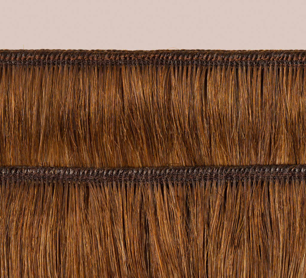 Side view of a caramel brown loose wave install past the shoulder