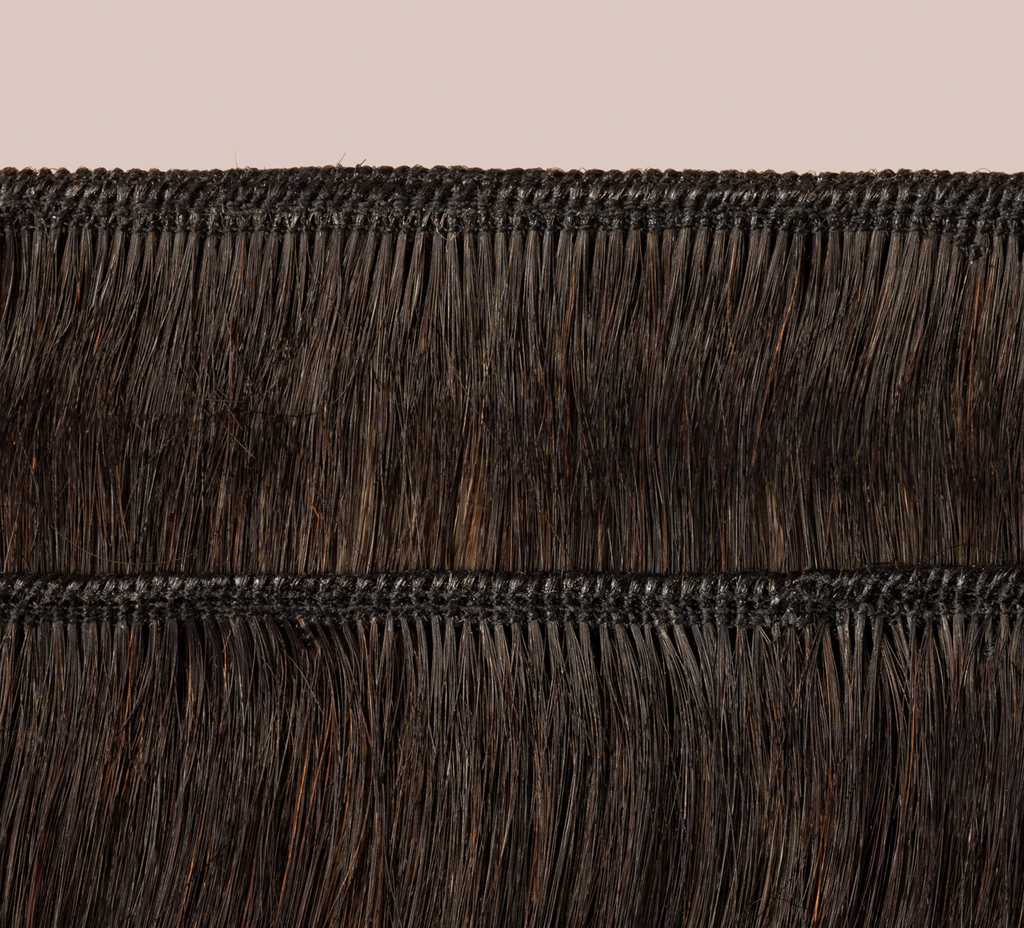 Natural black Brazilian curly bundle coiled on a plain background