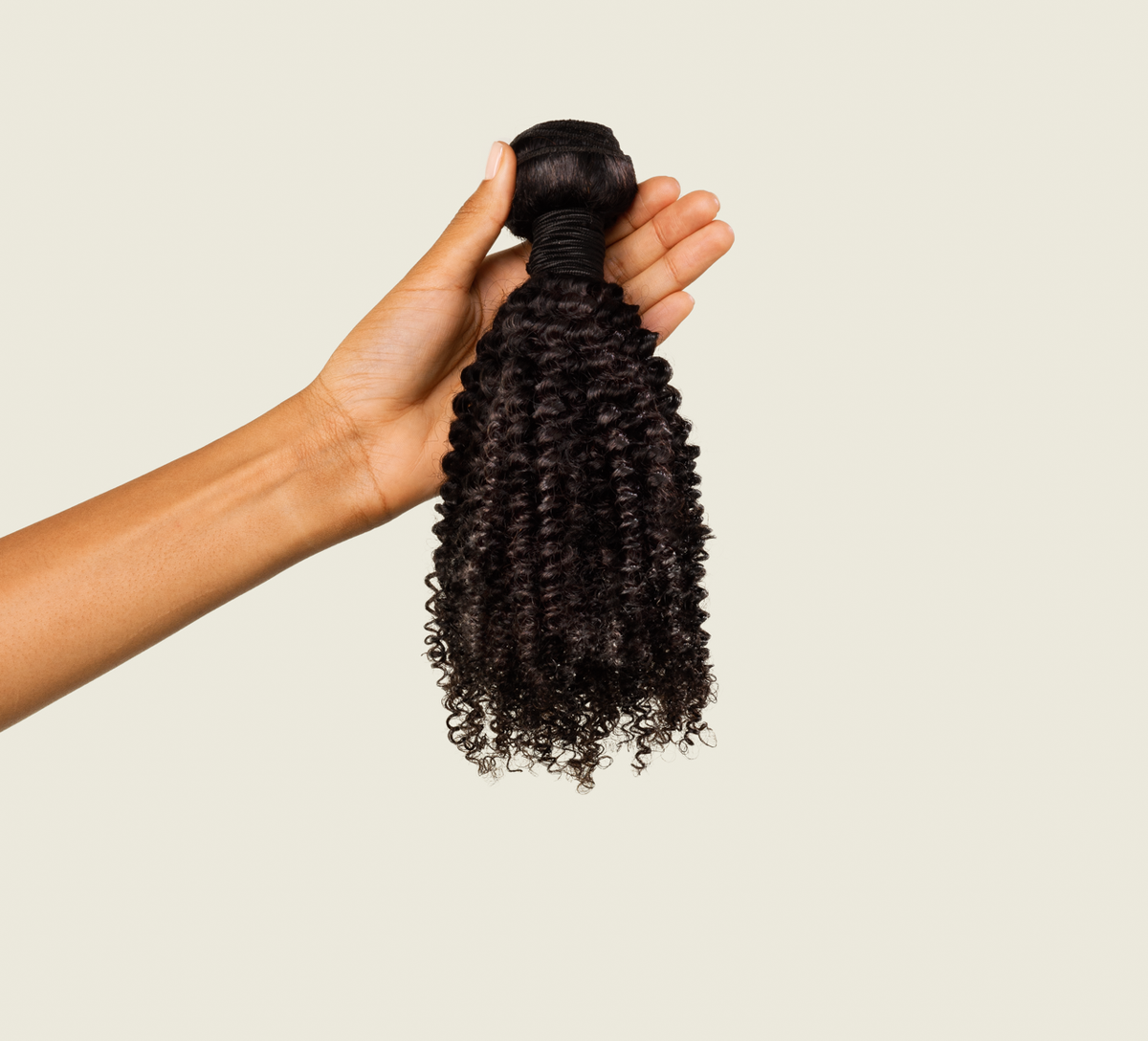Hand holding a natural black Brazilian curly bundle to show the weft